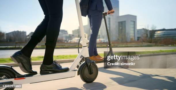 baja sección de hombre y mujer montando patinete eléctrico en la ciudad - mobility scooter fotografías e imágenes de stock