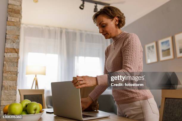 woman closing her laptop after using it - closed laptop stock pictures, royalty-free photos & images