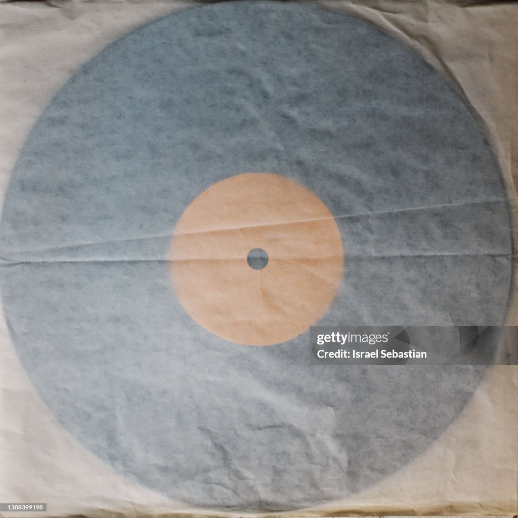 Top view of a vinyl record tucked into its old paper sleeve. The crumpled record sleeve has faded with age. Retro Style