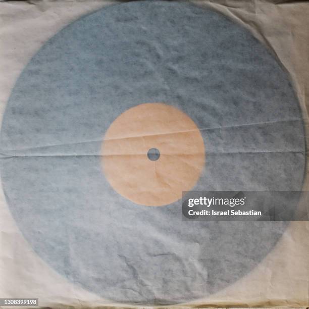 top view of a vinyl record tucked into its old paper sleeve. the crumpled record sleeve has faded with age. retro style - plastic sleeve stock pictures, royalty-free photos & images