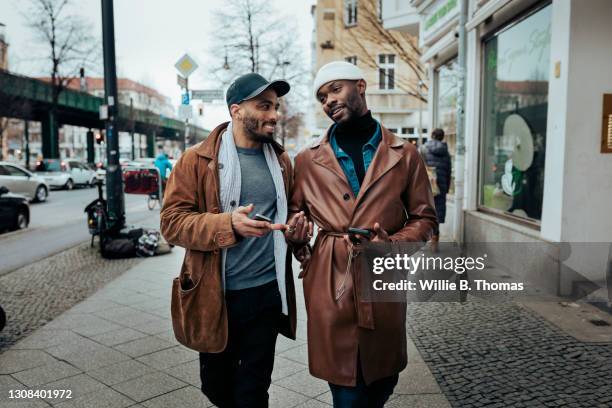 gay couple walking down street after meeting on dating app - brown trousers fotografías e imágenes de stock