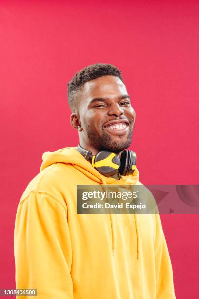 smiling black man with headphones in studio - happy man pink background stock pictures, royalty-free photos & images