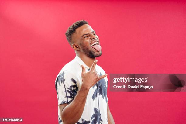expressive black man showing rock gesture in studio - língua - fotografias e filmes do acervo