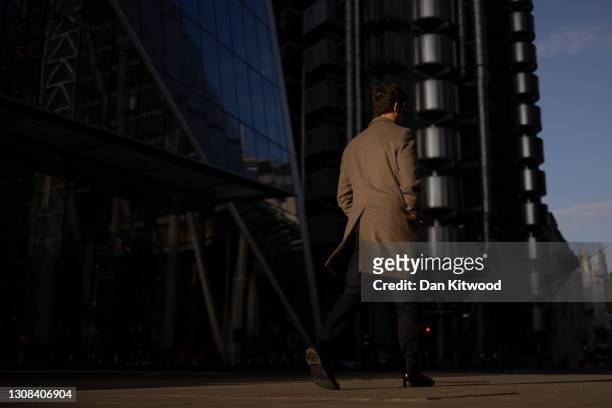 Man walks past the Lloyds of London building in the square mile on March 22, 2021 in London, England. A year since the British government issued its...