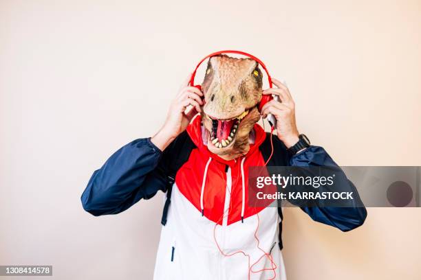 man with dinosaur mask looking at camera and putting on headphones - man with animal head stock pictures, royalty-free photos & images