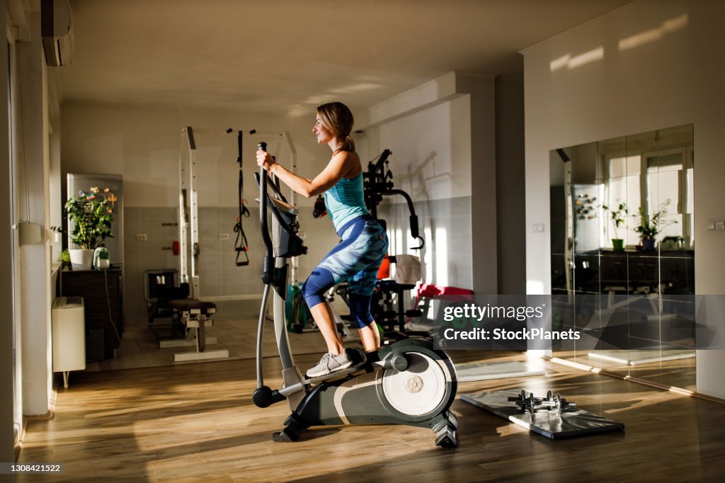 Glückliche athletische Frau Radfahren auf Heimtrainer