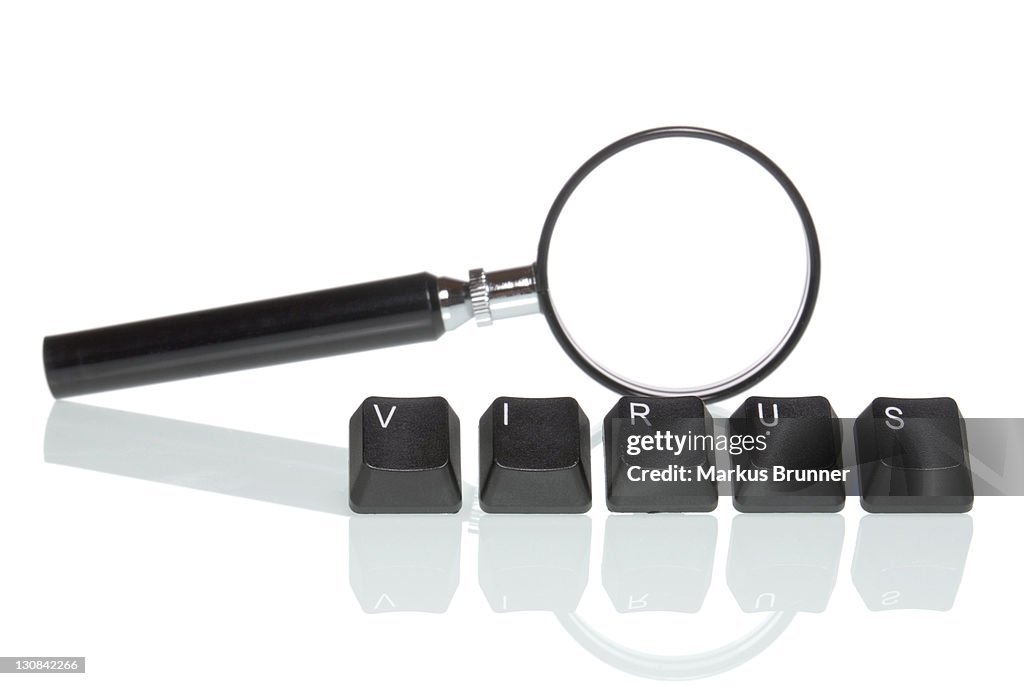 Magnifying glass behind keyboard buttons that spell virus