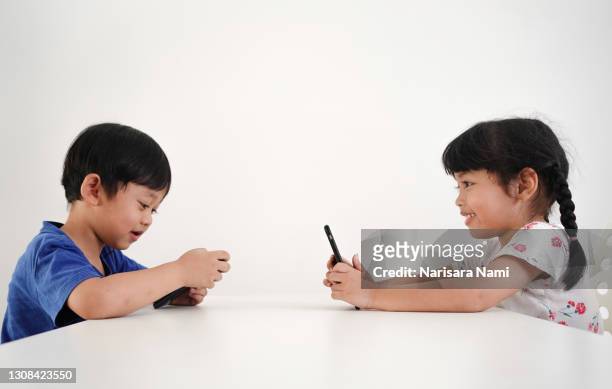 asian children play smartphone and online game. - asian twins 個照片及圖片檔
