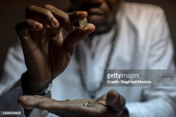 Diamond and gold dealer inspects diamonds in his shop on March 15, 2021 in the capital Bangui, Central African Republic. The United Nations estimates...