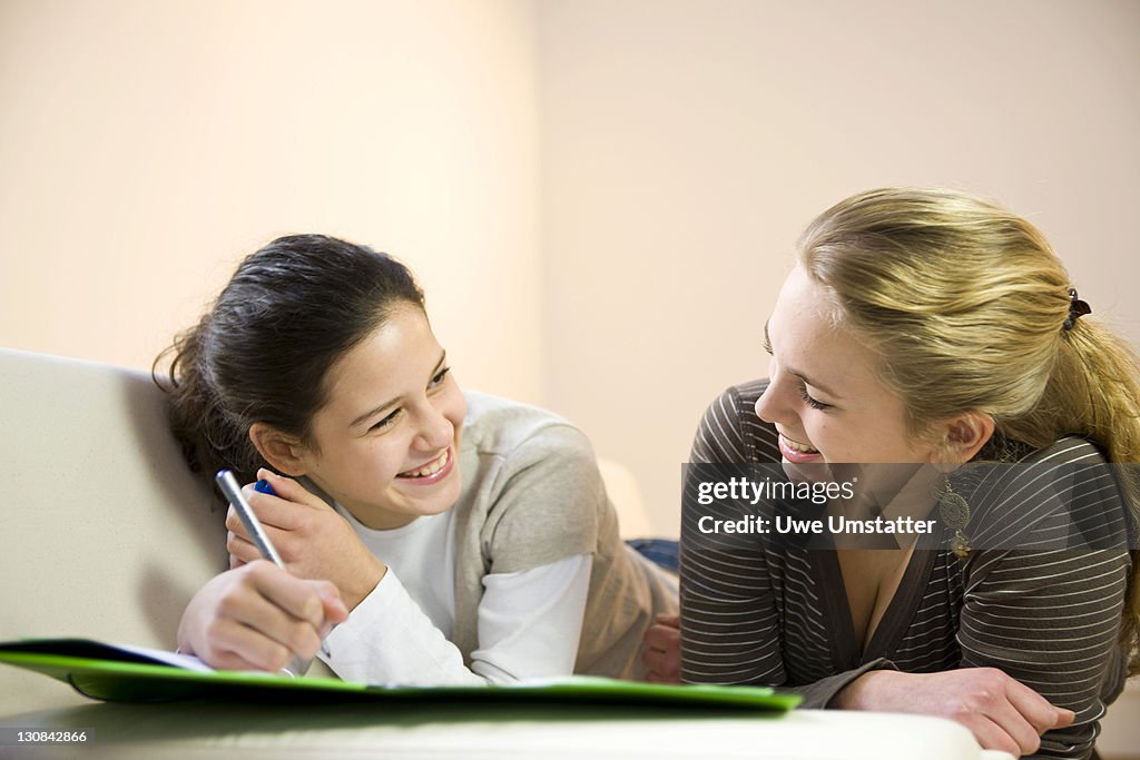 Two Make Homework Two Girls Doing Homework Together On The Sofa High-Res Stock Photo ...
