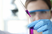 Researcher drips purple liquid from pipette into test tube