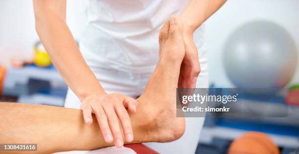 close-up of woman massaging mature man's foot - tornozelo imagens e fotografias de stock
