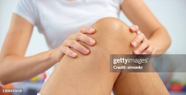 close-up of woman's hands massaging mature man's knee - standing with hands on knees imagens e fotografias de stock