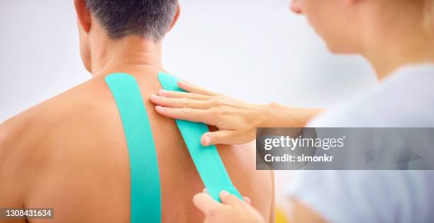 close-up of woman's hands applying kinesio tape - kinesiotape stock pictures, royalty-free photos & images