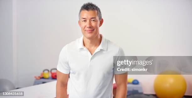 hombre sonriente de pie en centro de rehabilitación - camisa de polo fotografías e imágenes de stock