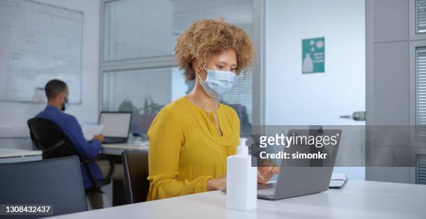 businesswoman working on laptop in office - businesswoman mask stock pictures, royalty-free photos & images