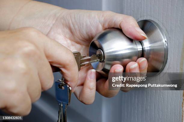 woman unlocking entrance door with a key. person using key and locking apartment door. - tecla de ordenador fotografías e imágenes de stock