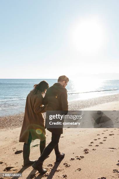 walk by the beach - couple walking on beach stock pictures, royalty-free photos & images