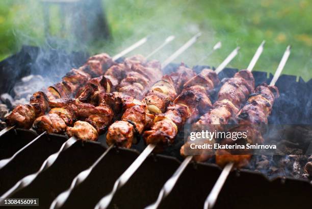 closeup of grilled meat shashliks on fire, summer time barbecue - schaschlik stock-fotos und bilder