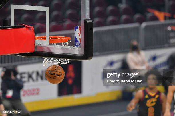 An official Spalding basketball falls through the net next to the NBA logo during the first quarter of the game between the Cleveland Cavaliers and...