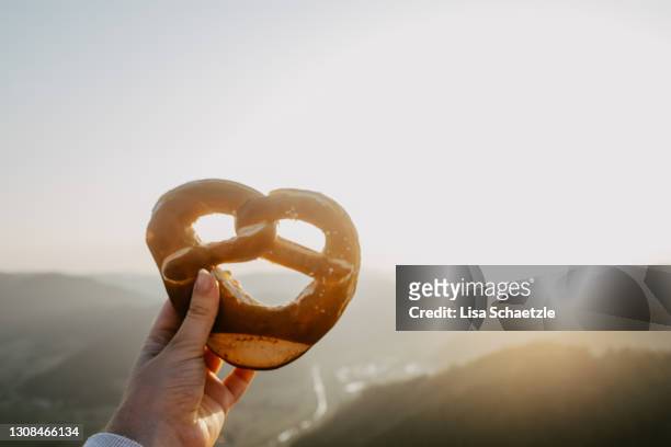 close-up of hand holding pretzel - breze stock-fotos und bilder