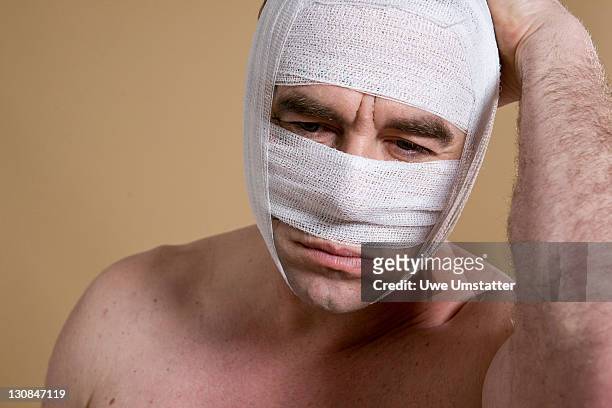 sad man with a bandaged face after a cosmetic surgery - plastic surgery stockfoto's en -beelden