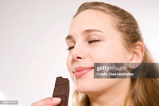 teenage girl enjoying a piece of chocolate - chocolate face imagens e fotografias de stock