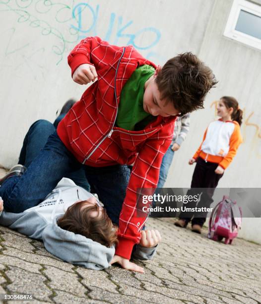 two boys arguing in the schoolyard, a girl watching - aggressione foto e immagini stock