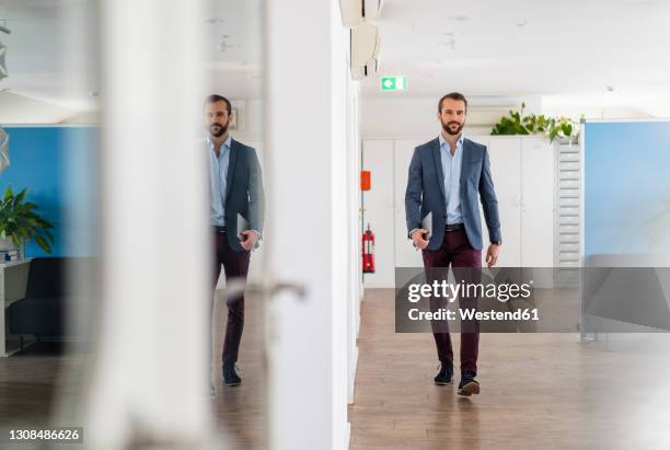 young businessman walking with digital tablet at office - distrarre lo sguardo foto e immagini stock