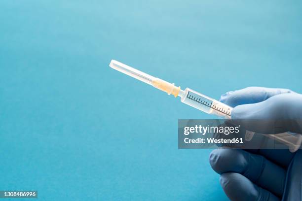 hand of person wearing protective glove holding single syringe - baby vaccination stock pictures, royalty-free photos & images