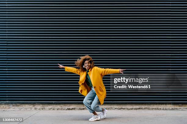 cheerful afro woman with arms outstretched having fun against wall - auscultador equipamento áudio imagens e fotografias de stock