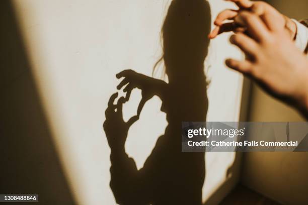 child creating a heart shape shadow on a white wall - hands in heart shape stock pictures, royalty-free photos & images