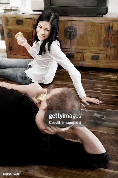 young couple listening to music together and eating an apple - pale complexion stock-fotos und bilder