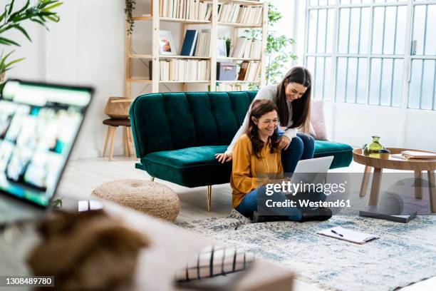 cheerful daughter assisting mother using laptop at home - family budget stock pictures, royalty-free photos & images