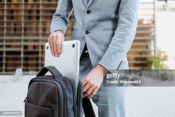 businessman taking out laptop from back pack - mochila-bolsa fotografías e imágenes de stock
