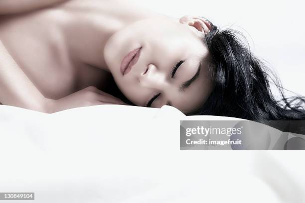 young dark-haired woman lying with eyes closed, portrait - pale complexion stock-fotos und bilder