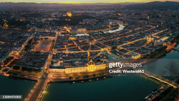 france, auvergne-rhone-alpes, lyon, aerial view of illuminated city situated at confluence of rhone andsaonerivers at dusk - lyon stock-fotos und bilder