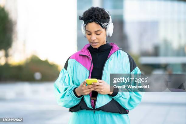 cool young woman using mobile phone in city - blue coat stock pictures, royalty-free photos & images