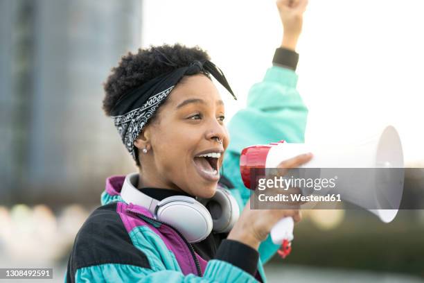 young woman doing announcement through megaphone - aktivist stock-fotos und bilder