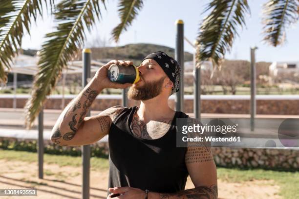 thirsty male sportsperson having energy drink in park on sunny day - energy drink stock pictures, royalty-free photos & images
