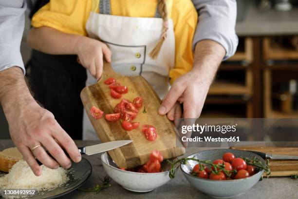 mature man helping girl while preparing food standing in kitchen at home - generationen kochen stock-fotos und bilder
