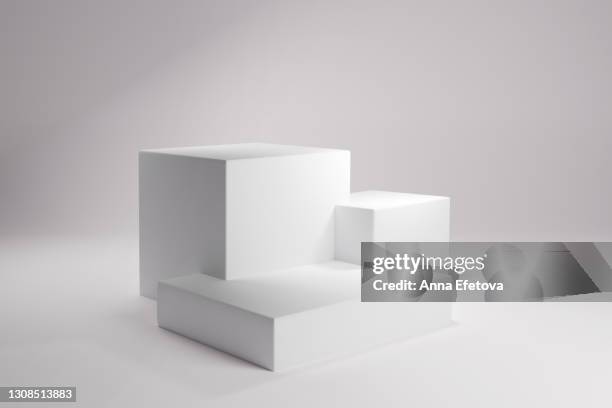 three white square podiums or stages for cosmetics over clean background with sun light. perfect for demonstrating your product. front view. three dimensional - cube fotografías e imágenes de stock