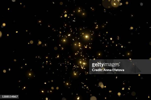 glittering golden confetti on black isolated background. christmas and new year concept in trendy festive golden color. - glänzend stock-fotos und bilder