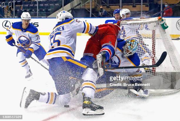 Carter Hutton of the Buffalo Sabres is injured during the first period as Rasmus Ristolainen checks Julien Gauthier of the New York Rangers in the...