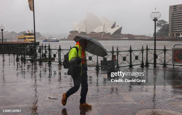 Man walks to work in Circular Quay carrying an umbrella to shelter from the driving rain on March 23, 2021 in Sydney, Australia. Evacuation warnings...