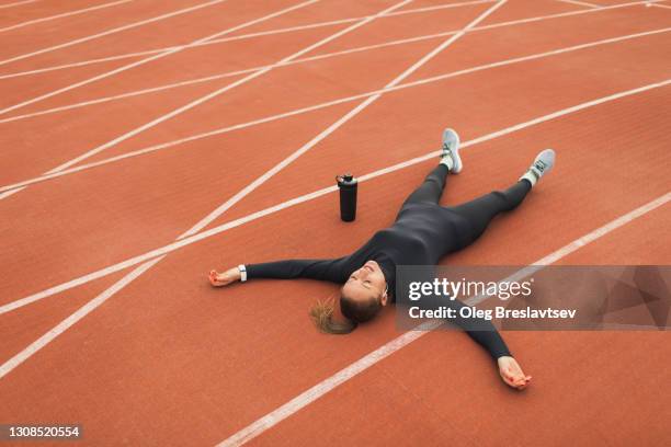 tired and despair woman lying on running track of stadium after hard workout - indecisive stock-fotos und bilder