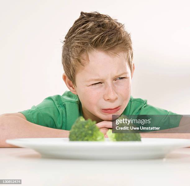 boy sitting in front of a plate of broccoli with a disgusted look on his face - 10 11 years stock pictures, royalty-free photos & images