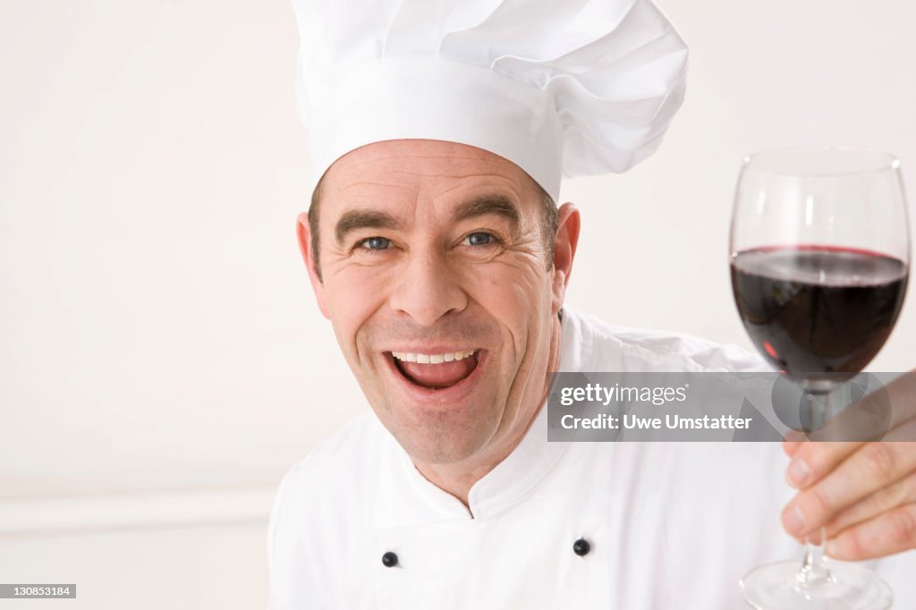 Laughing cook holding a glass of red wine
