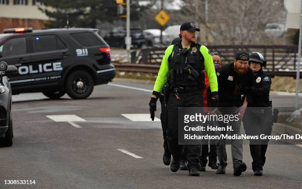 People who were inside the King Soopers are escorted down the street by Boulder Police after being taken out of the supermarket after a shooting in...