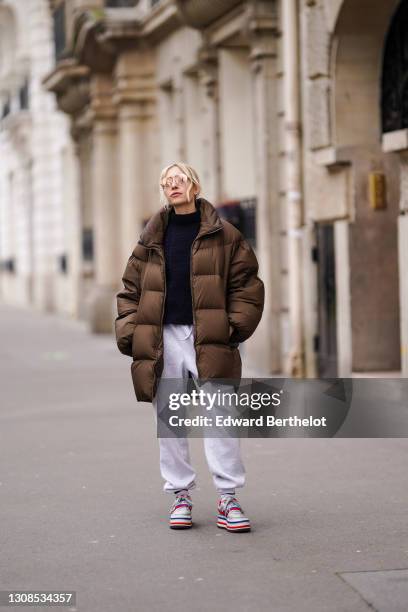 Emy Venturini wears sunglasses, a navy blue woven turtleneck pullover, gray jogger sportswear pants, Nike black red and white striped platform...